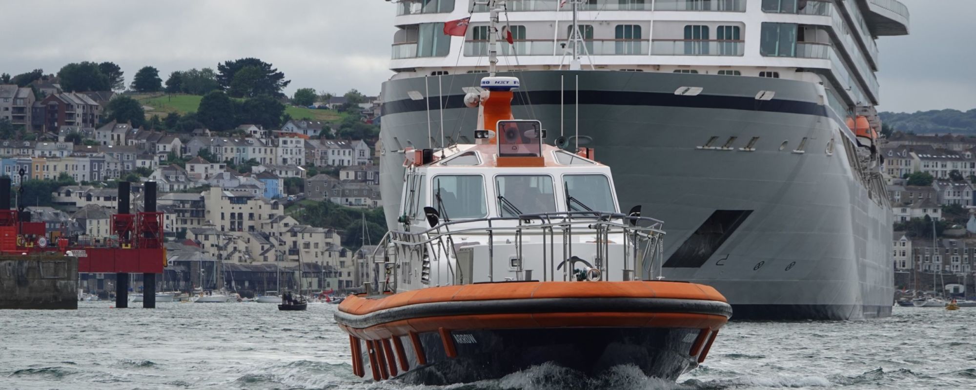 Pilot boat ahead of a cruise ship in Falmouth Harbour
