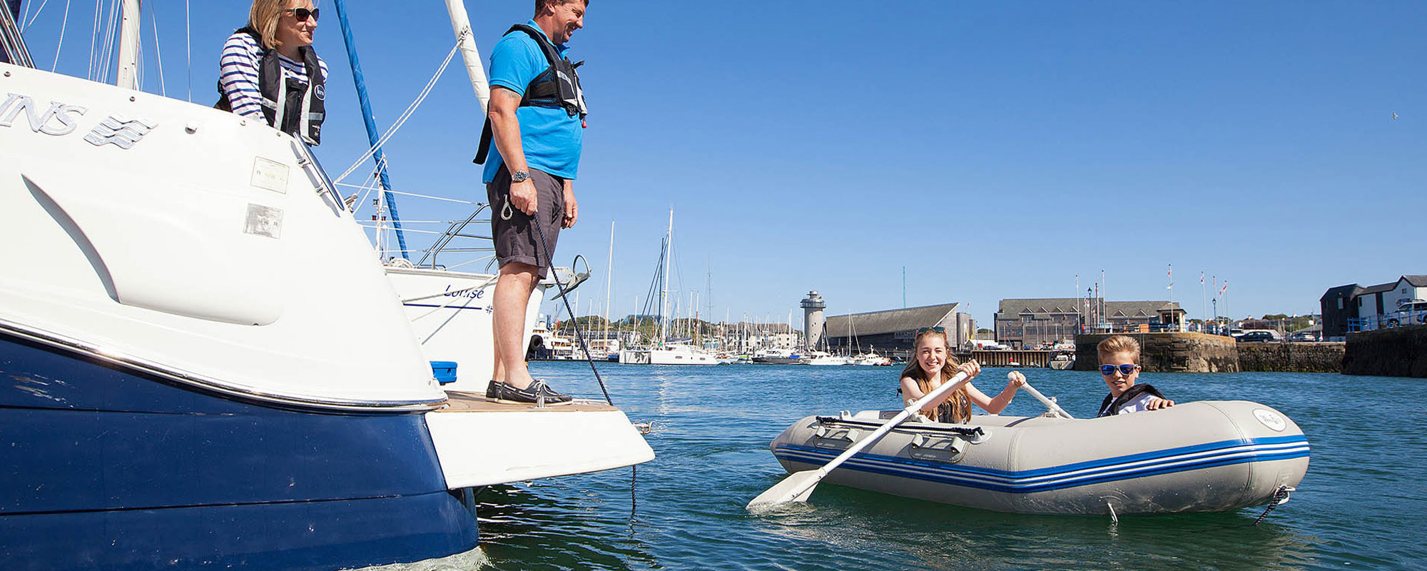 Children in a tender with parents looking on from yacht